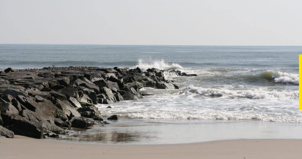 Natural rock jettie intersects waves off a sand beach